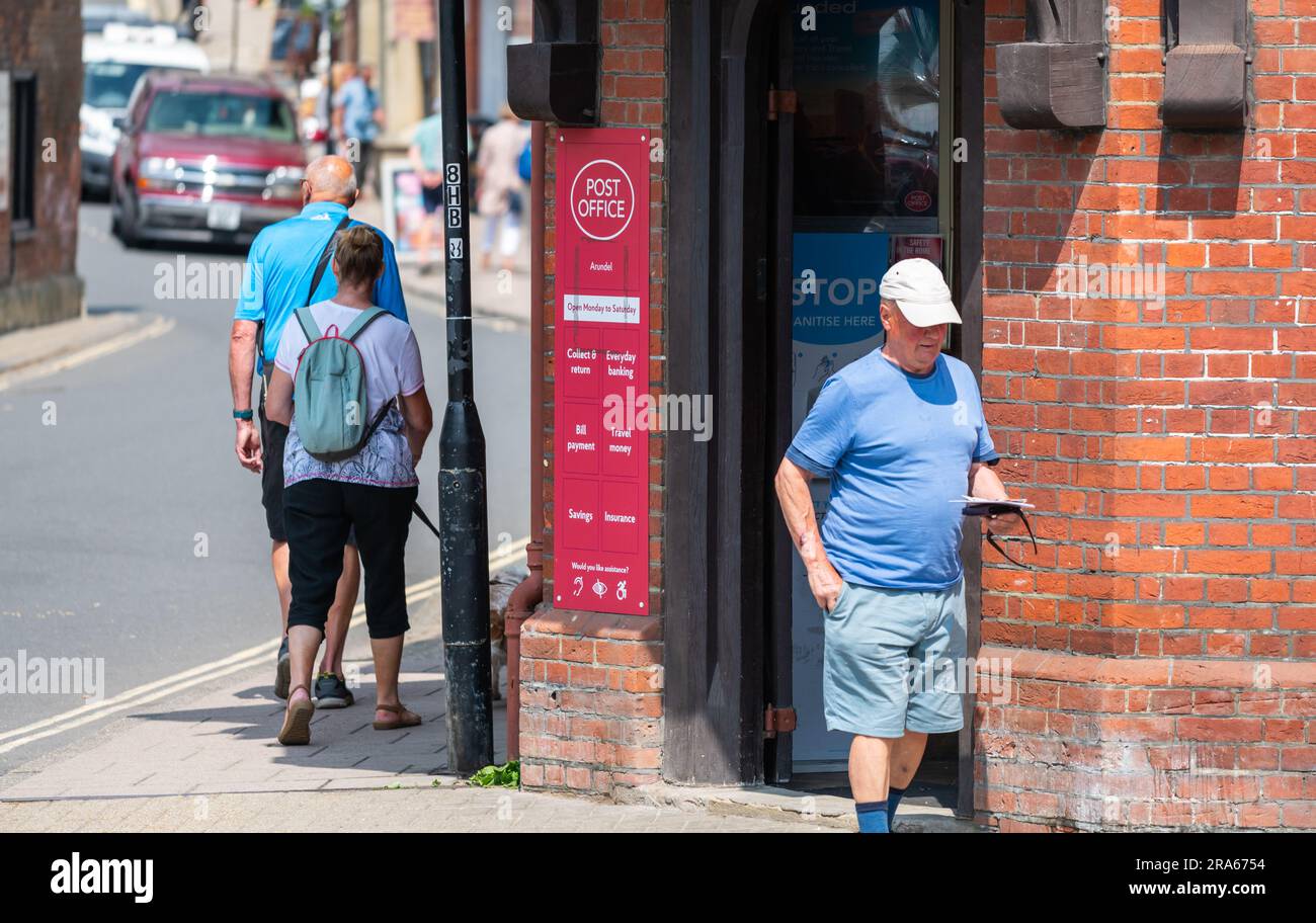 Ein Mann, der aus einem Postgebäude in der britischen Marktstadt Arundel, West Sussex, England, geht. Stockfoto