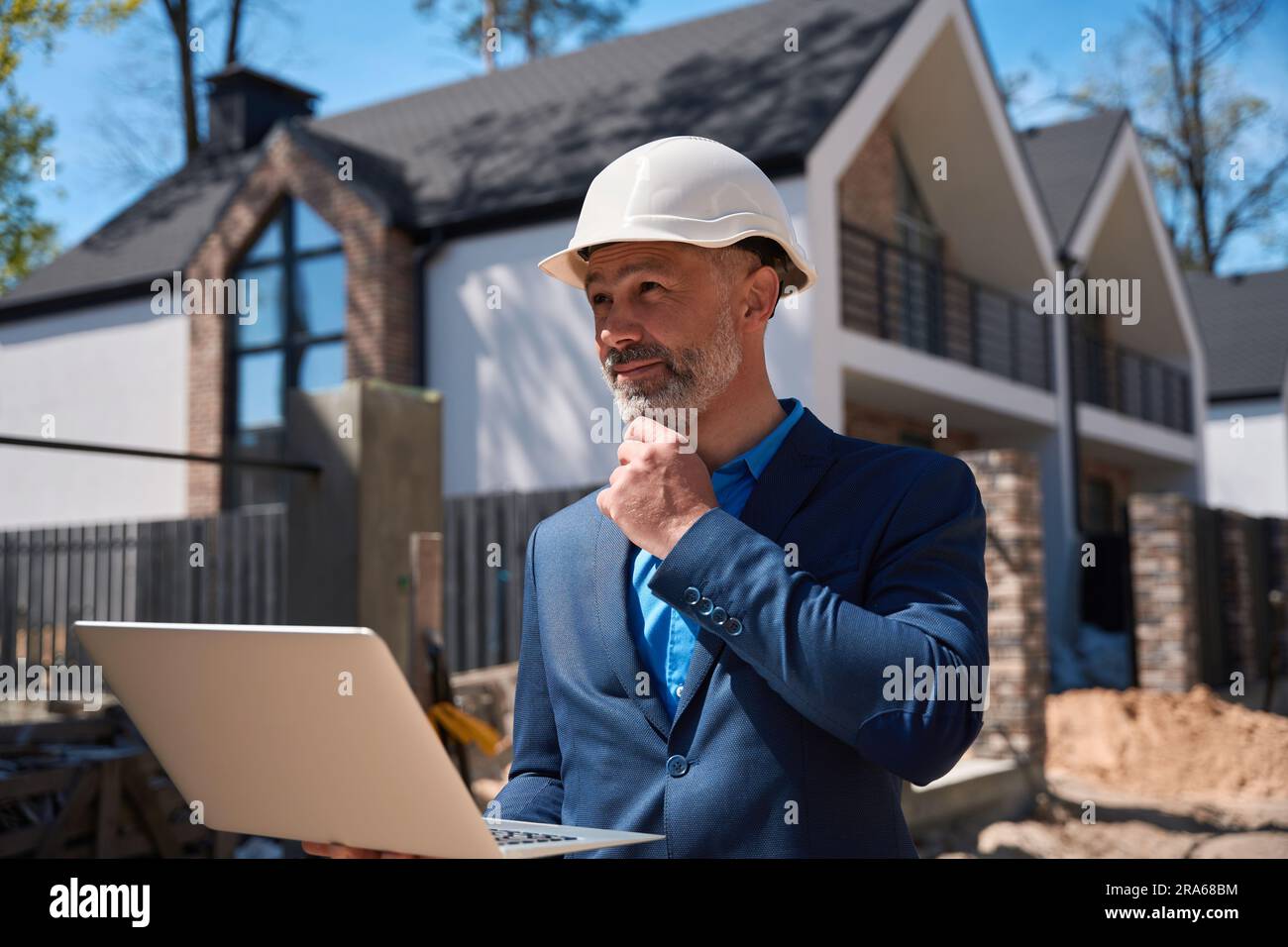 Architekt auf der Baustelle mit Schutzhelm, mit Laptop Stockfoto