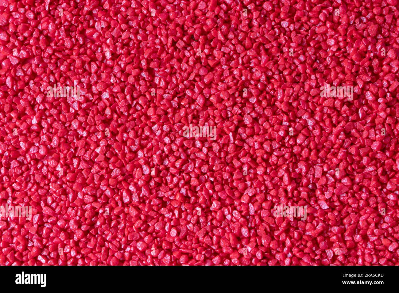 Roter dekorativer, glänzender Blumensteinhintergrund. Kleine natürliche Kieselsteine mit abgerundeten Kanten. Stockfoto