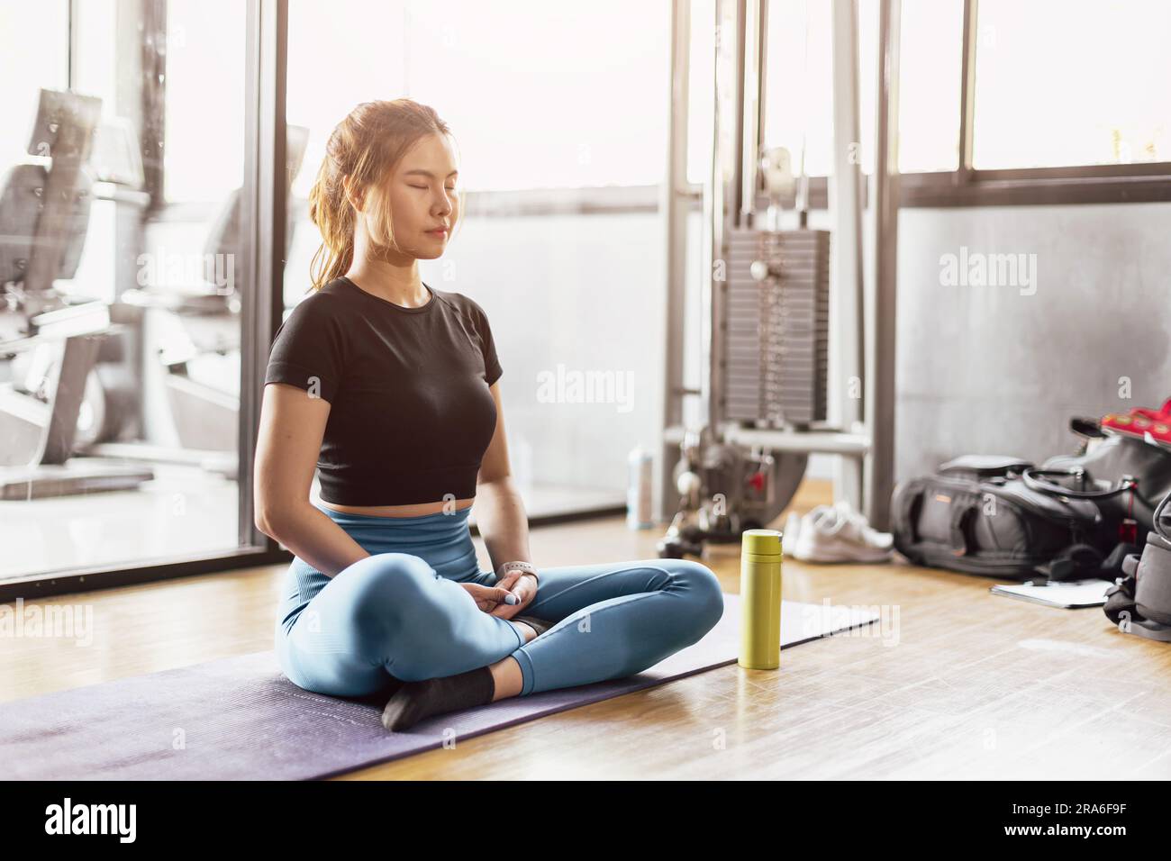 Junge asiatische Frau, die Yoga praktiziert, sitzt in Meditationsübungen, Ruhe, Ruhe, Entspannung, posieren, trainieren in Sportbekleidung, Meditationssitzung im Hallensport Stockfoto