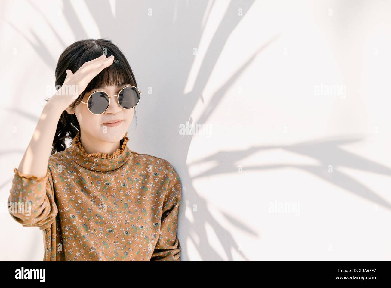 Asiatisches Teenager-Mädchen mit Sonnenbrille im Vintage-Kleid am Baum Sonnenschirm schatten die Leute der Sommersaison. Stockfoto