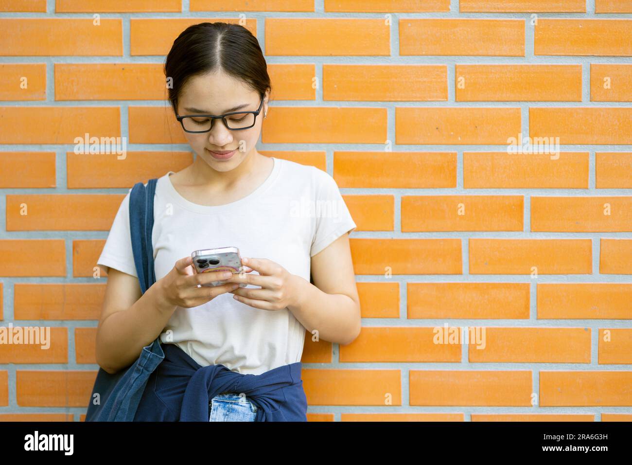 Asiatische Studentinnen an der Teenager-Universität spielen gern Smartphone-Nachrichten-Kontakte mit Freunden. Stockfoto