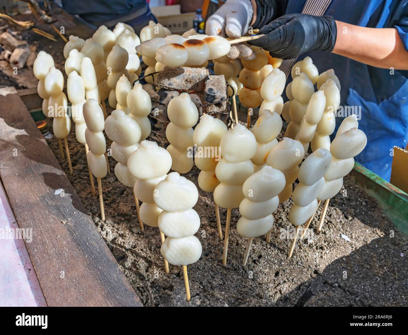 Ladenbesitzer grillen auf Holzkohle, traditionelle japanische Spießklöße aus Reismehl, Wagashi-Konfekt namens kushi-Dango, wenn auf Spieß oder sumibi-y Stockfoto