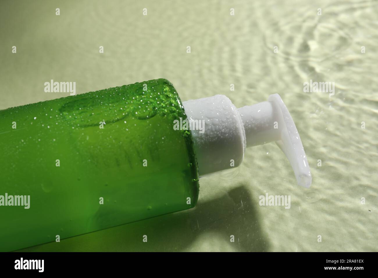 Eine Flasche Gesichtsreiniger in Wasser vor olivem Hintergrund, Nahaufnahme Stockfoto