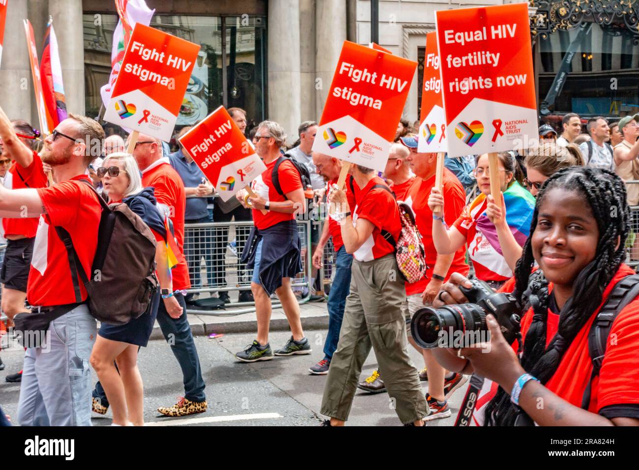 Die Teilnehmer der jährlichen London Pride-Veranstaltung am 1. Juli 2023 in London tragen rote Plakate, die bessere Rechte für HIV-positive Menschen fordern Stockfoto