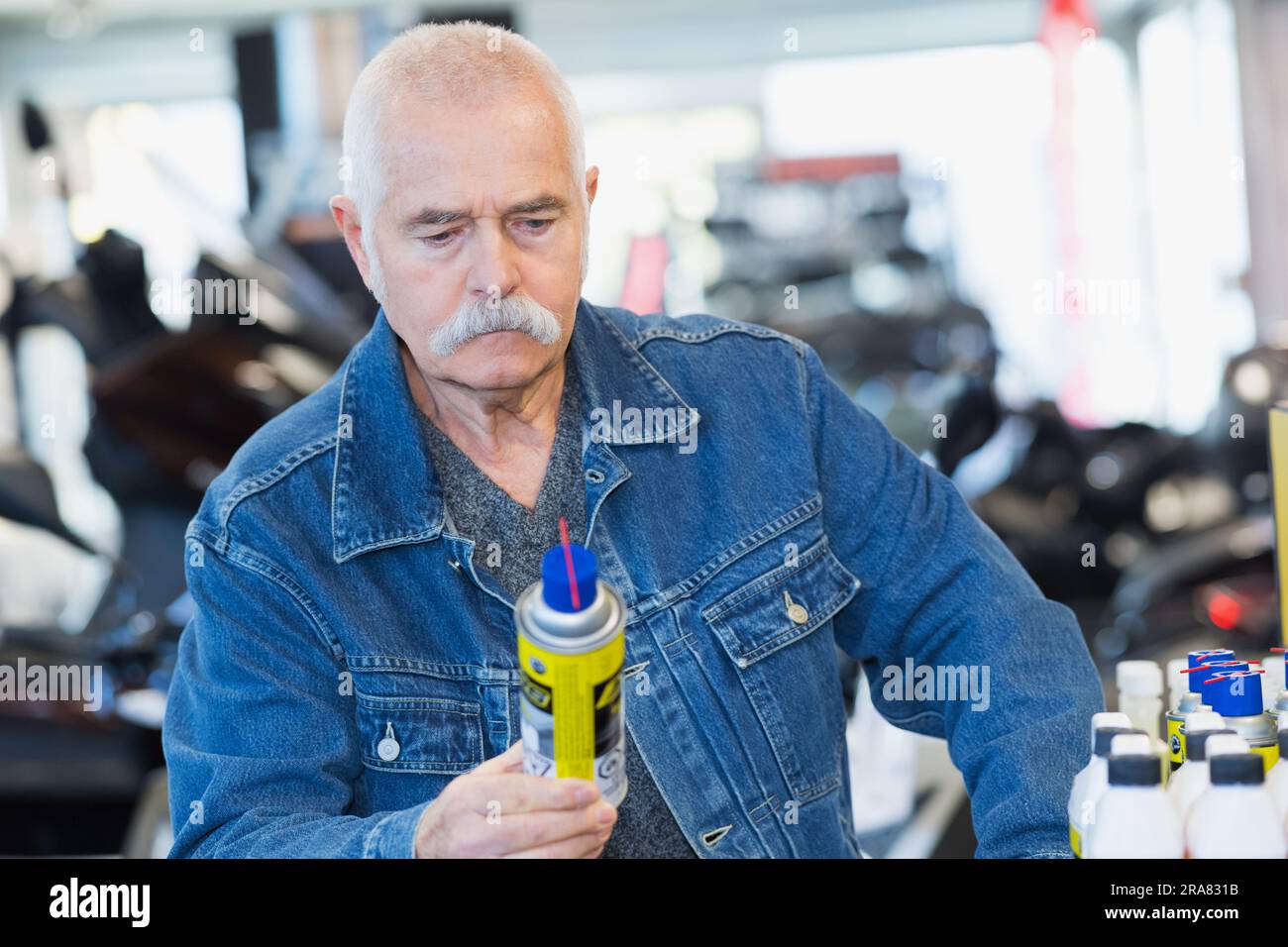 Ein Senior-Mann, der sich ein Automobil-Schmiermittel-Spray ansieht Stockfoto