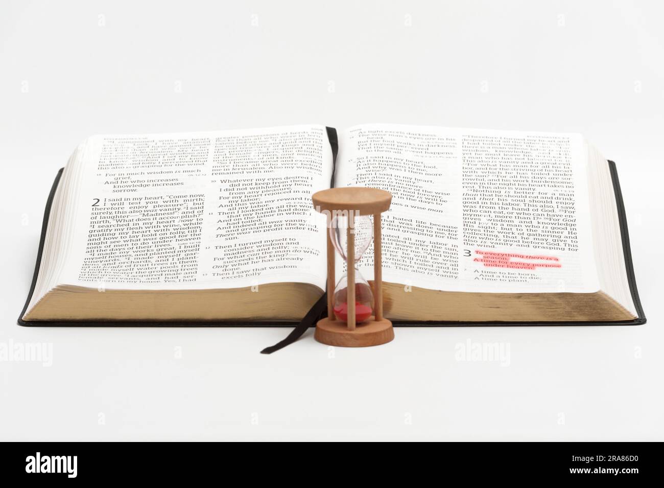 Sanduhr und offene bibel über das Buch des Kirchenlehrers mit selektivem Fokus auf Vers 1 von Kapitel 3, rot hervorgehoben. Isoliert auf weißem Hintergrund. Stockfoto