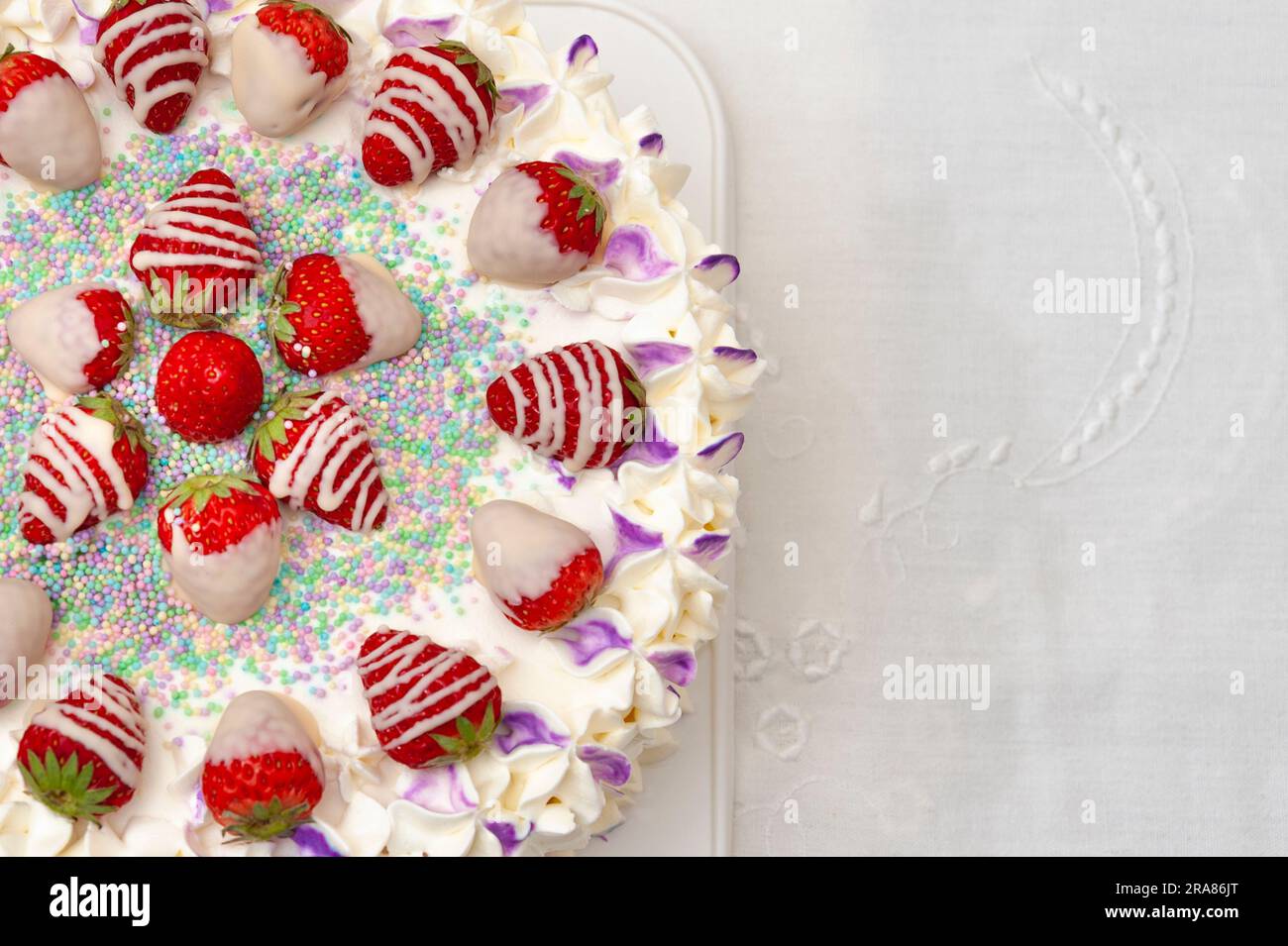 Happy Birthday to you: Wunderschön dekorierter Kuchen mit Erdbeeren und Confetti. Stockfoto