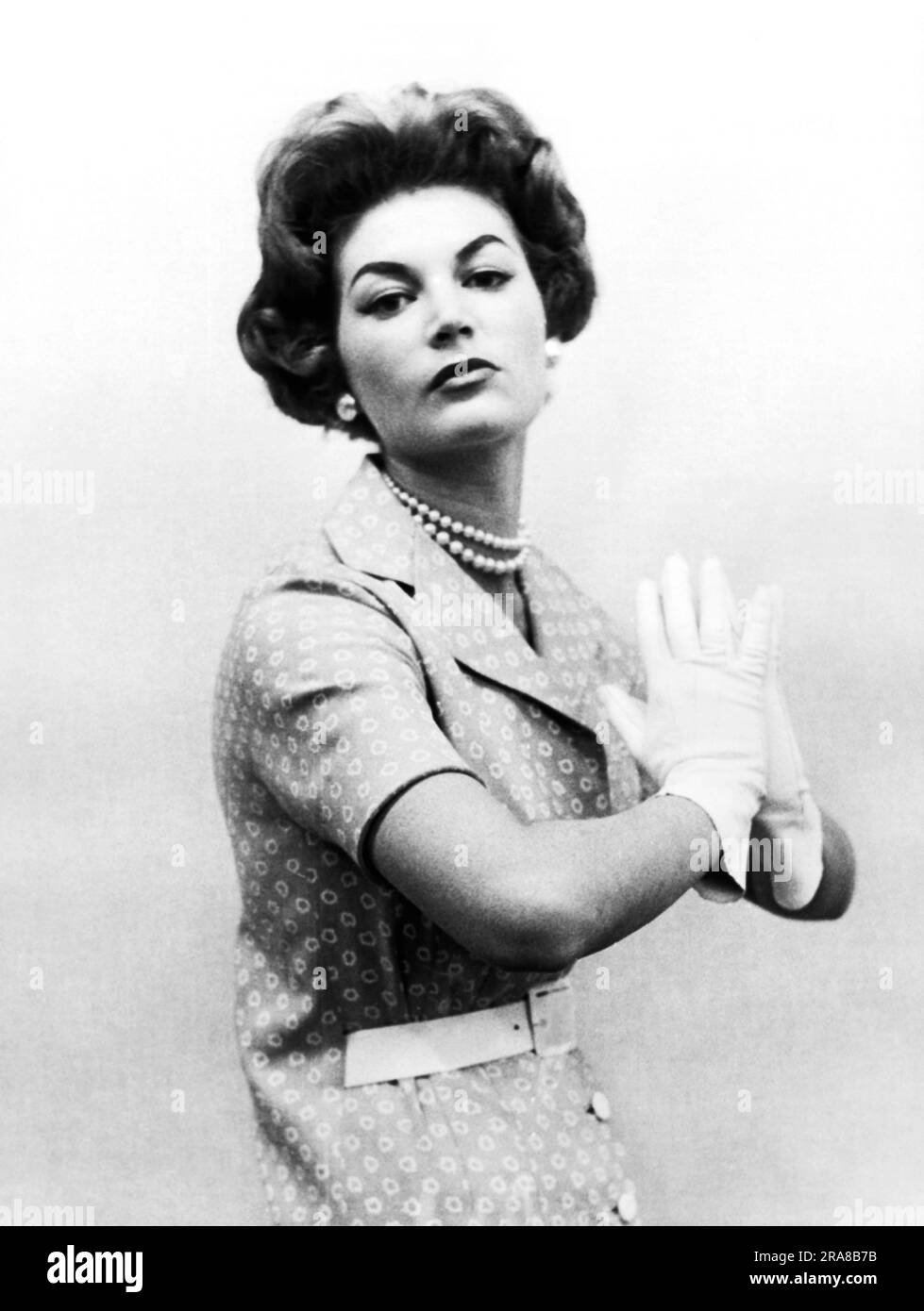 New York, New York, 9. Januar 1958 Ein Modell mit Perlen und weißen Handschuhen, das ein blaues Leinenkleid mit Hannah Troy-Aufdruck trägt, das mit oder ohne Gürtel getragen werden kann. Stockfoto