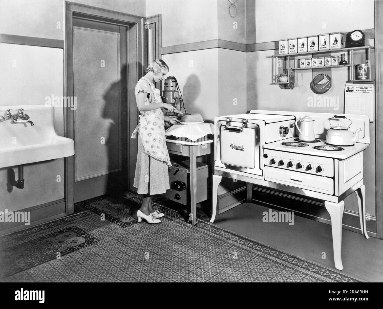 Beaver Dam, Wisconsin: ca. 1927. Eine Frau schneidet einen Kuchen, den sie in ihrem Monarchofen gebacken hat. Stockfoto
