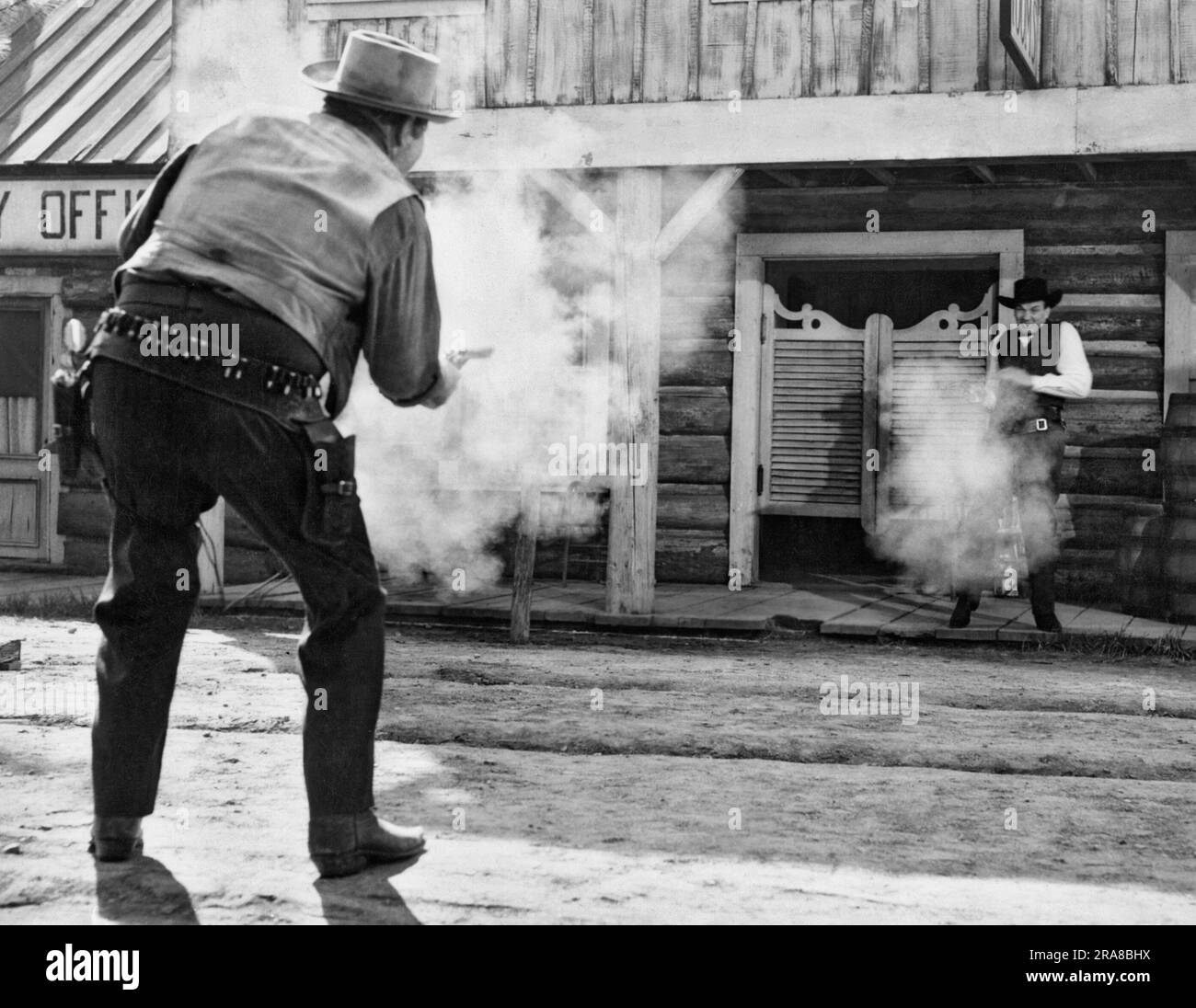 Hollywood, Kalifornien: ca. 1950 der gute Cowboy (Lichthut) scheint in dieser Western-Filmszene vor den Türen des Saloons die Anziehungskraft auf den bösen Cowboy (dunkler Hut) zu ziehen. Stockfoto