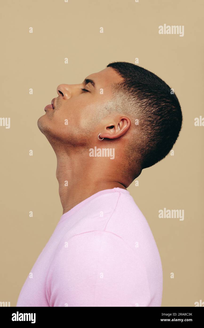 Selbstbewusster junger Mann, der in einem Studio steht, mit einem makellosen Hautton, der sein Engagement für eine tägliche Hautpflege zeigt. Hübscher junger Mann, Embracin Stockfoto