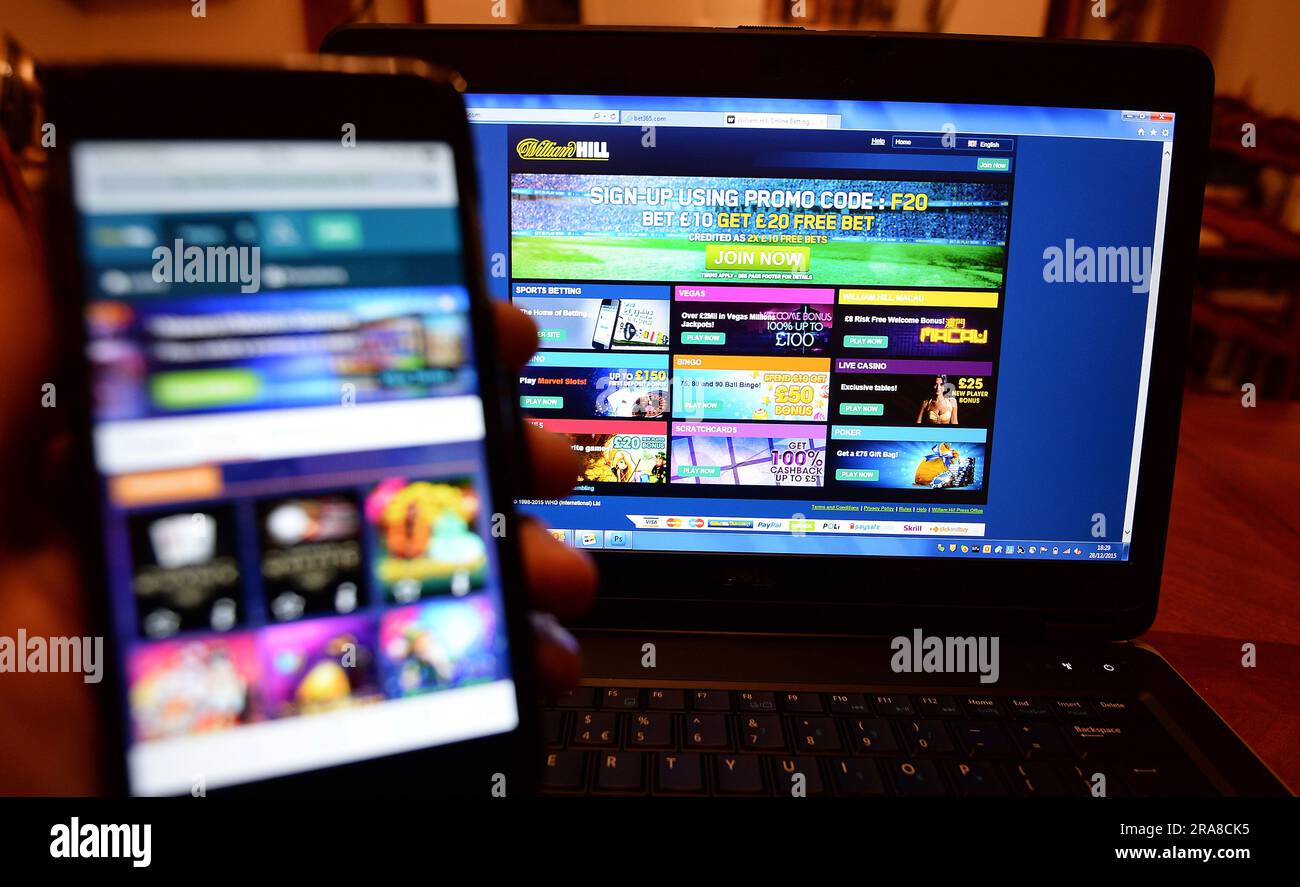 Datei Foto vom 28/12/15 der William Hill Glücksspiel-Website auf einem Telefon und einem Laptop, als Gesundheitsbeamte Bedenken darüber geäußert haben, dass Kinder und Erwachsene mit Glücksspielwerbung „bombardiert“ werden, nachdem eine Rekordzahl von Menschen in England Hilfe für Glücksspielsucht gesucht haben. Amanda Pritchard, Chefin von NHS England, machte auch Alarm wegen Wetten, als sie ankündigte, dass der NHS die Unterstützung für Menschen mit Spielproblemen erhöht. Ausgabedatum: Sonntag, 2. Juli 2023. Stockfoto