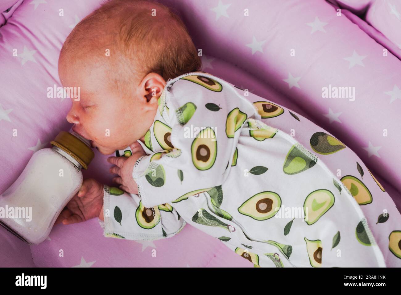 Ein Neugeborenes trinkt zu Hause unabhängig Milch oder eine trockene Mischung aus einer Flasche Stockfoto