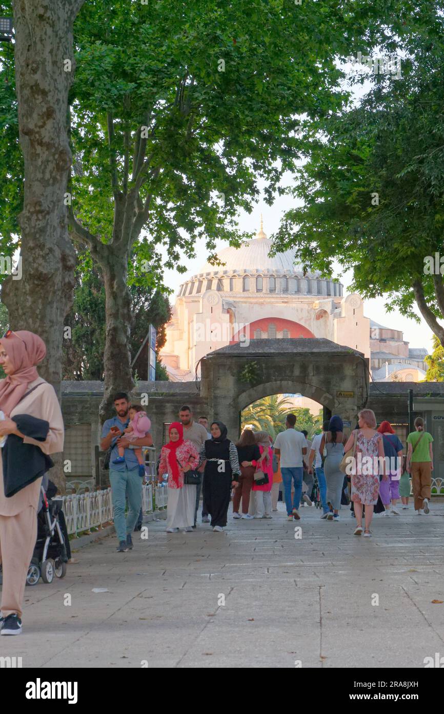 An einem Sommerabend spazieren die Menschen durch die Außenmauer der Blauen Moschee mit der Hagia Sophia Moschee im Hintergrund. Istanbul, Türkei. Stockfoto