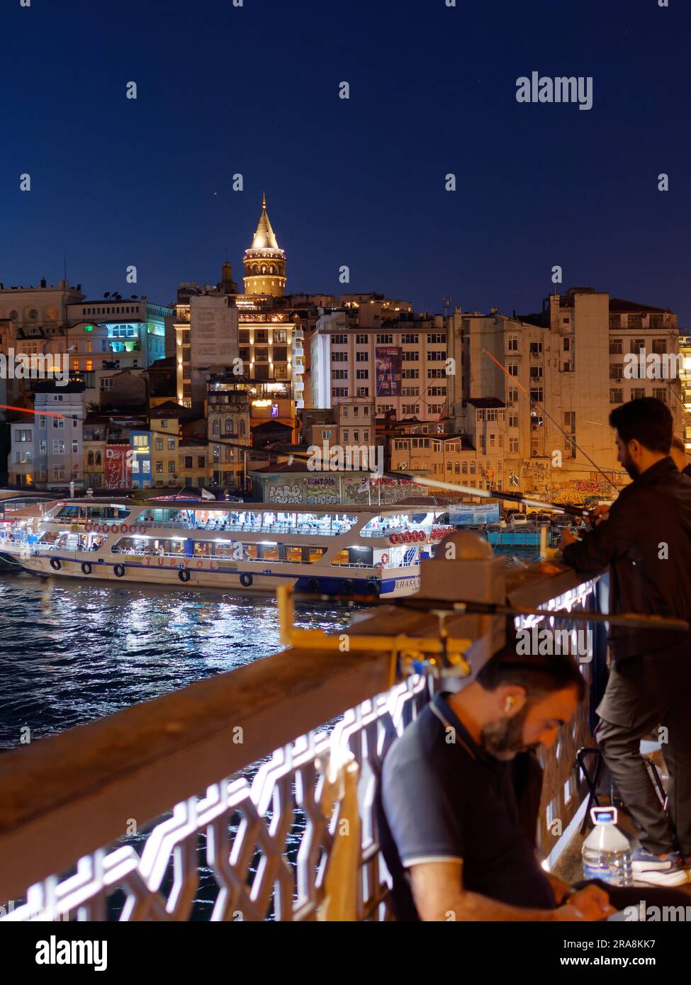 Fischer auf der Galata-Brücke über das Goldene Horn bei Nacht mit der Galata-Brücke dahinter, Istanbul, Türkei Stockfoto