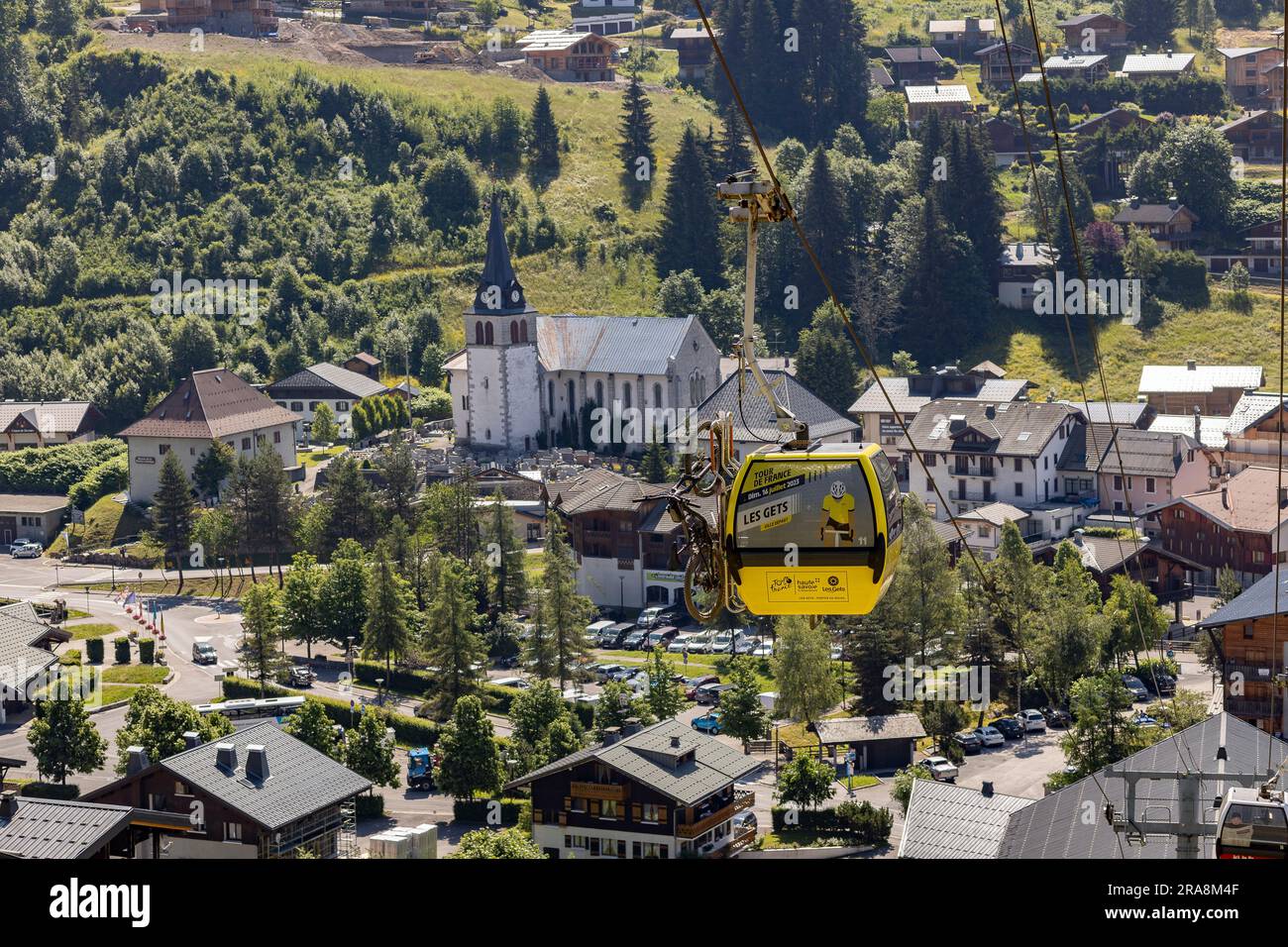 Gelbe Seilbahn mit Ankündigung der Tour de France und Off-Road-Fahrrädern über der französischen Alpenstadt Stockfoto