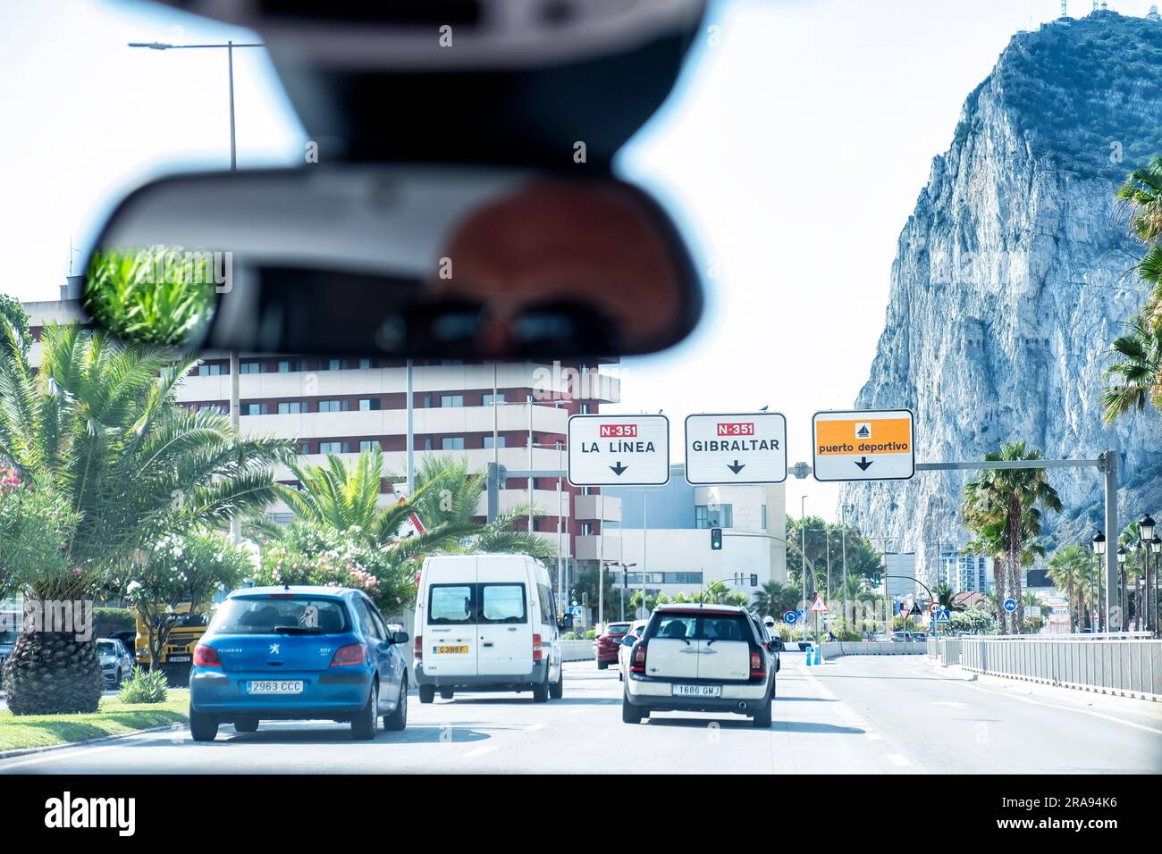 Ein Fahrzeug nähert sich der spanischen Grenze zu Gibraltar von der spanischen Seite der N-351. Der Felsen von Gibraltar erhebt sich auf dem Weg zum Grenzpunkt. Stockfoto