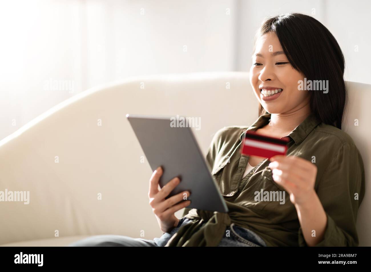 Nahaufnahme einer fröhlichen jungen asiatischen Frau, die online Bankgeschäfte tätigt Stockfoto