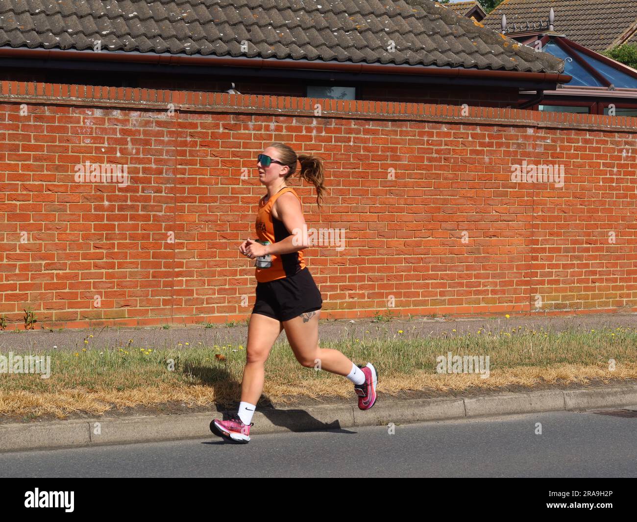 Kesgrave, Suffolk - 2. Juli 2023 : vom Laufverein Kesgrave Kruisers organisiertes Rennen zum Alan Brown Memorial 10k. Heißer Sommermorgen. Alleinstehende Läuferin. Stockfoto