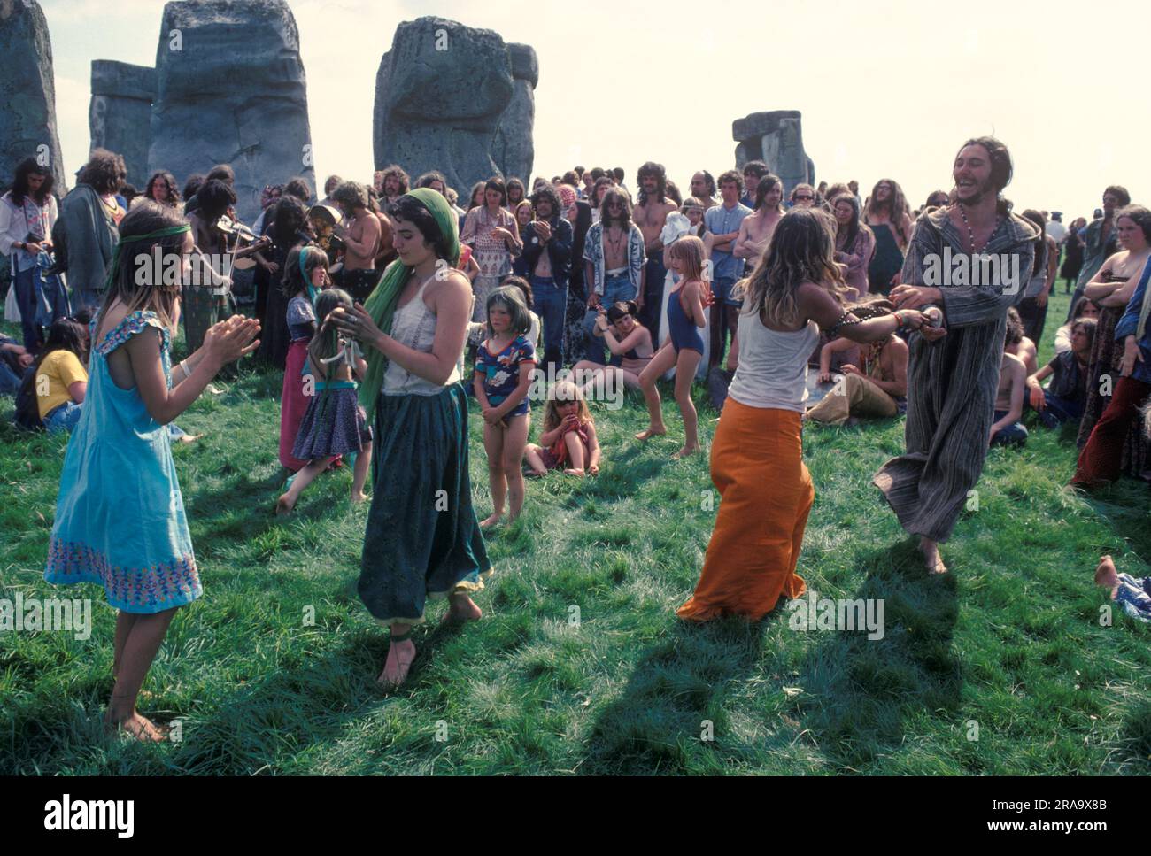 Stonehenge Free Festival zur Sommersonnenwende 1970 Eine kleine Gruppe von New Age Hippies im Stil der 1970er Jahre, eine Familiengruppe tanzen und feiern zusammen, während andere zusehen. Wiltshire, England, 21. Juni 1979. HOMER SYKES AUS DEN 70ER JAHREN Stockfoto