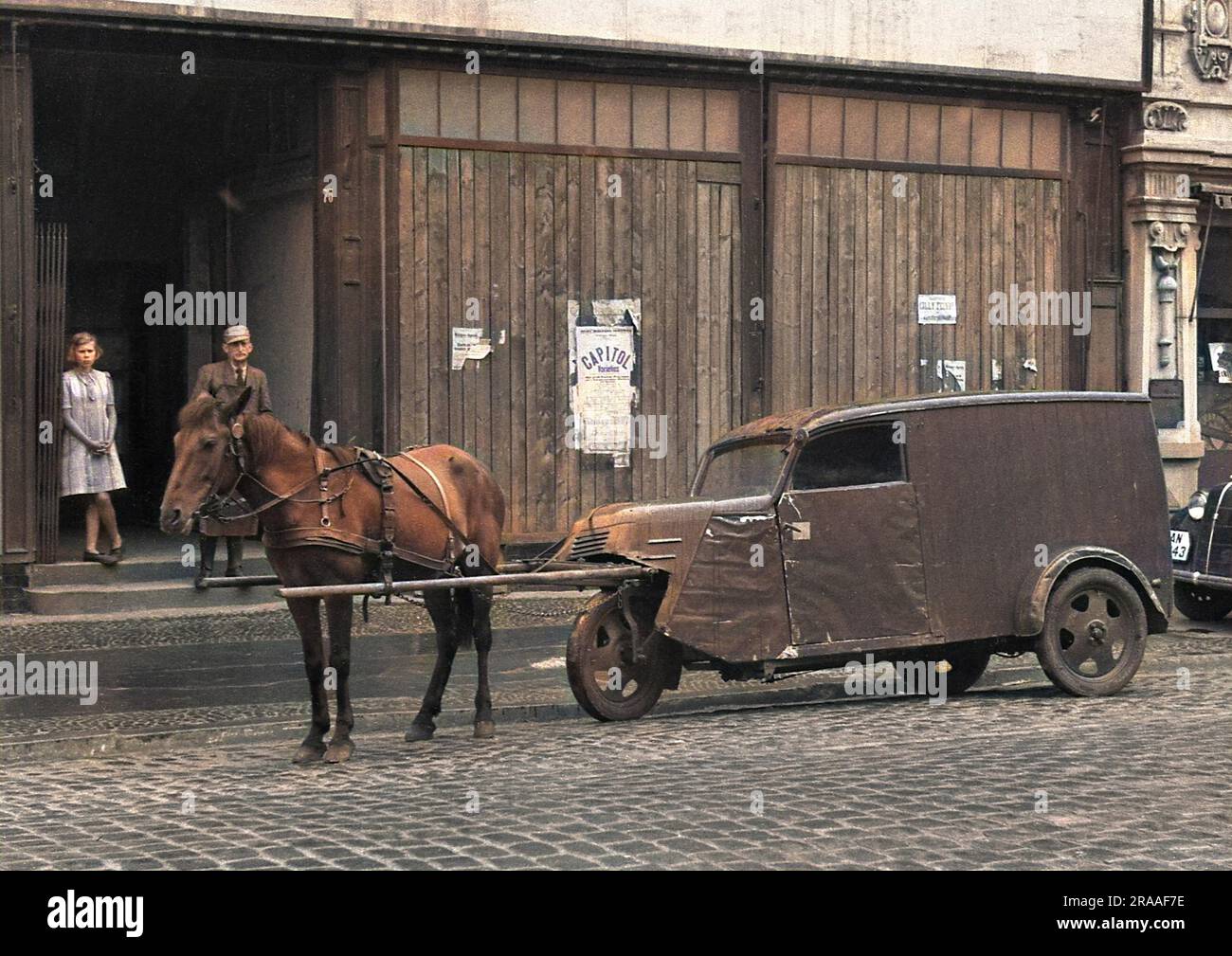 Ein Pferd, das ein dreirädriges Fahrzeug auf einer kopfsteingepflasterten Straße in Deutschland zieht. Datum: Ca. 1940er Stockfoto