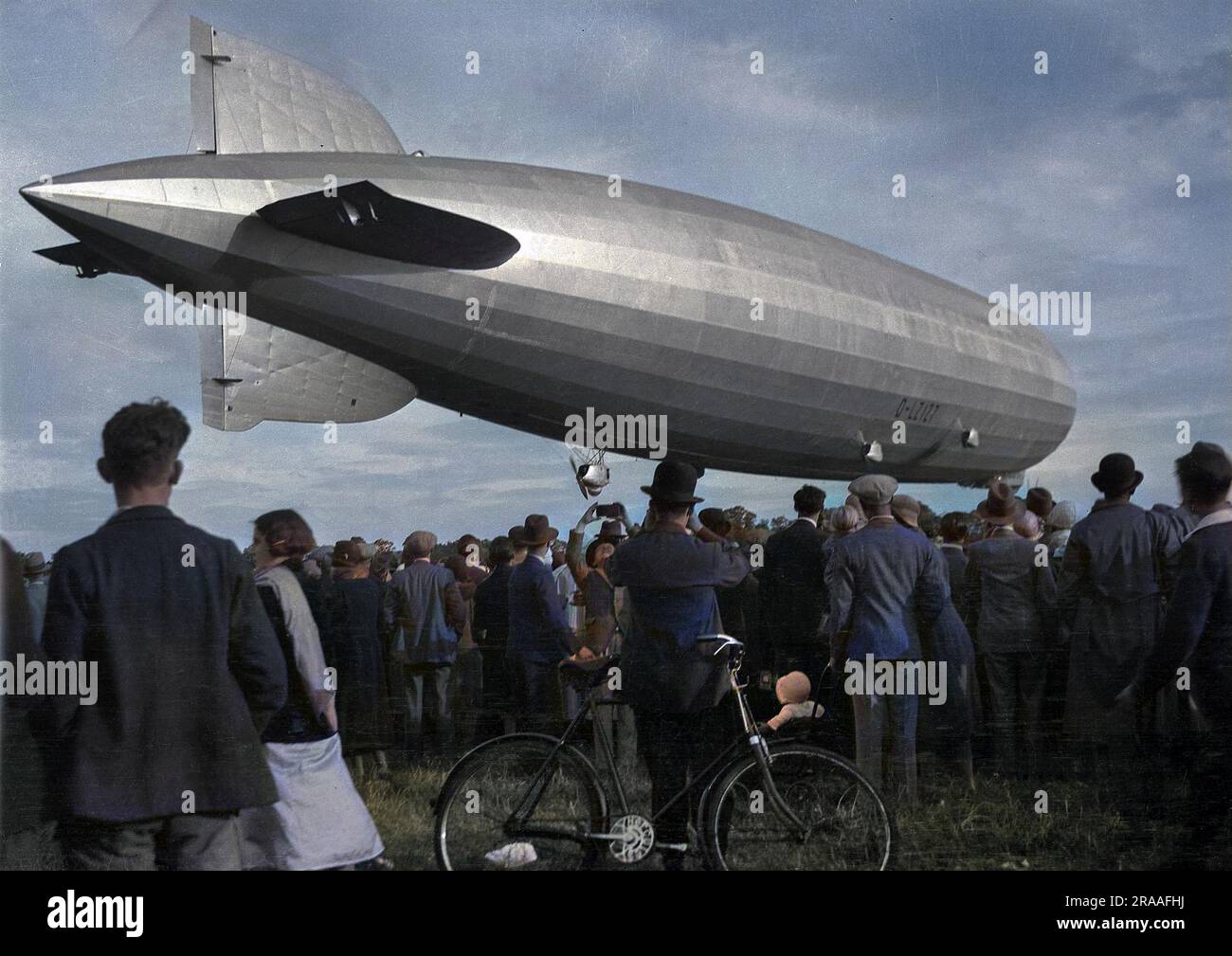 Das deutsche Luftschiff Graf Zeppelin schwebt über dem Boden, mit einer Menschenmenge darunter. Stockfoto