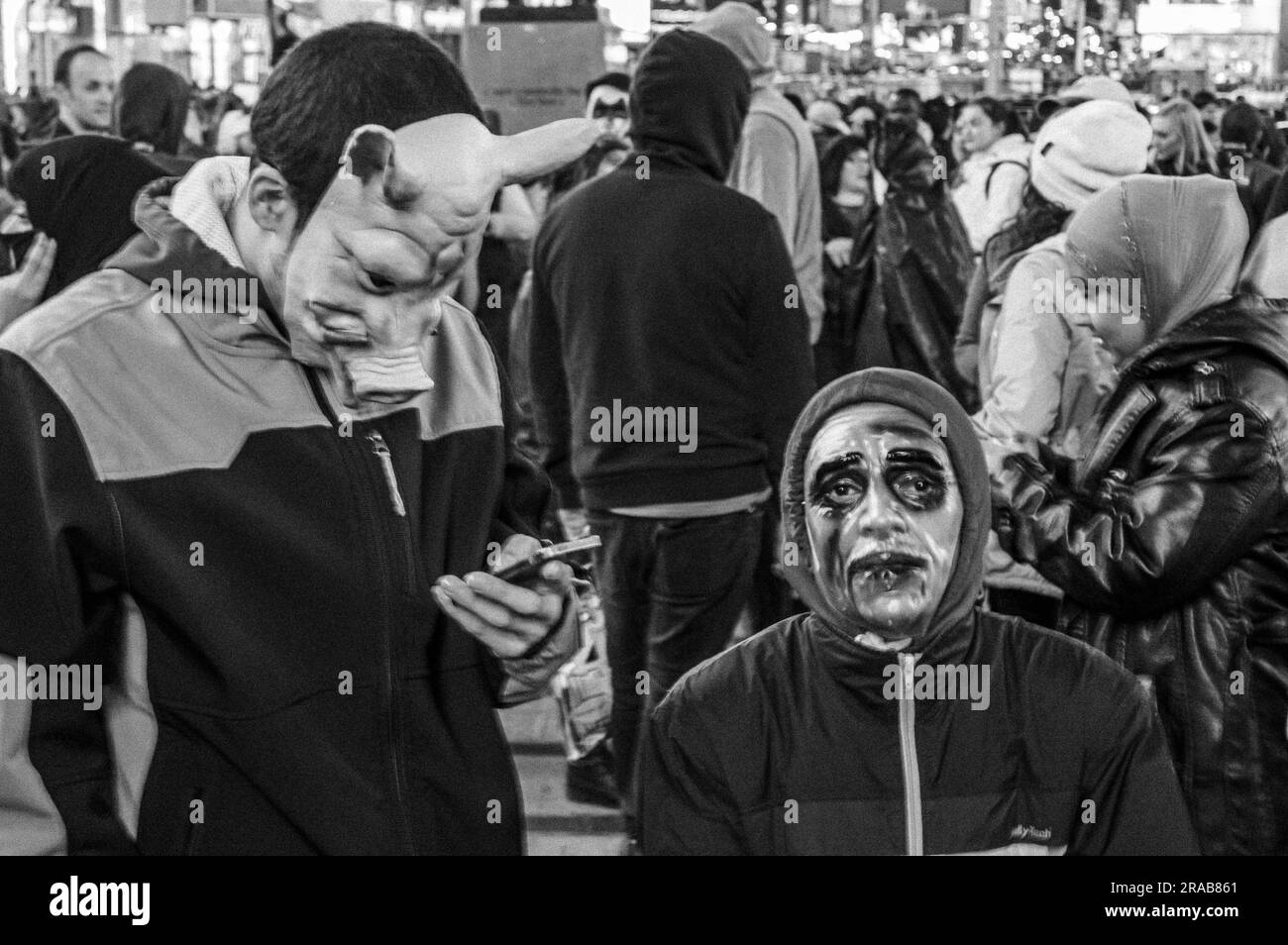 Zwei Leute mit Masken, einer überprüft sein Handy und stellt sich in Times Square auf. An Halloween. Stockfoto