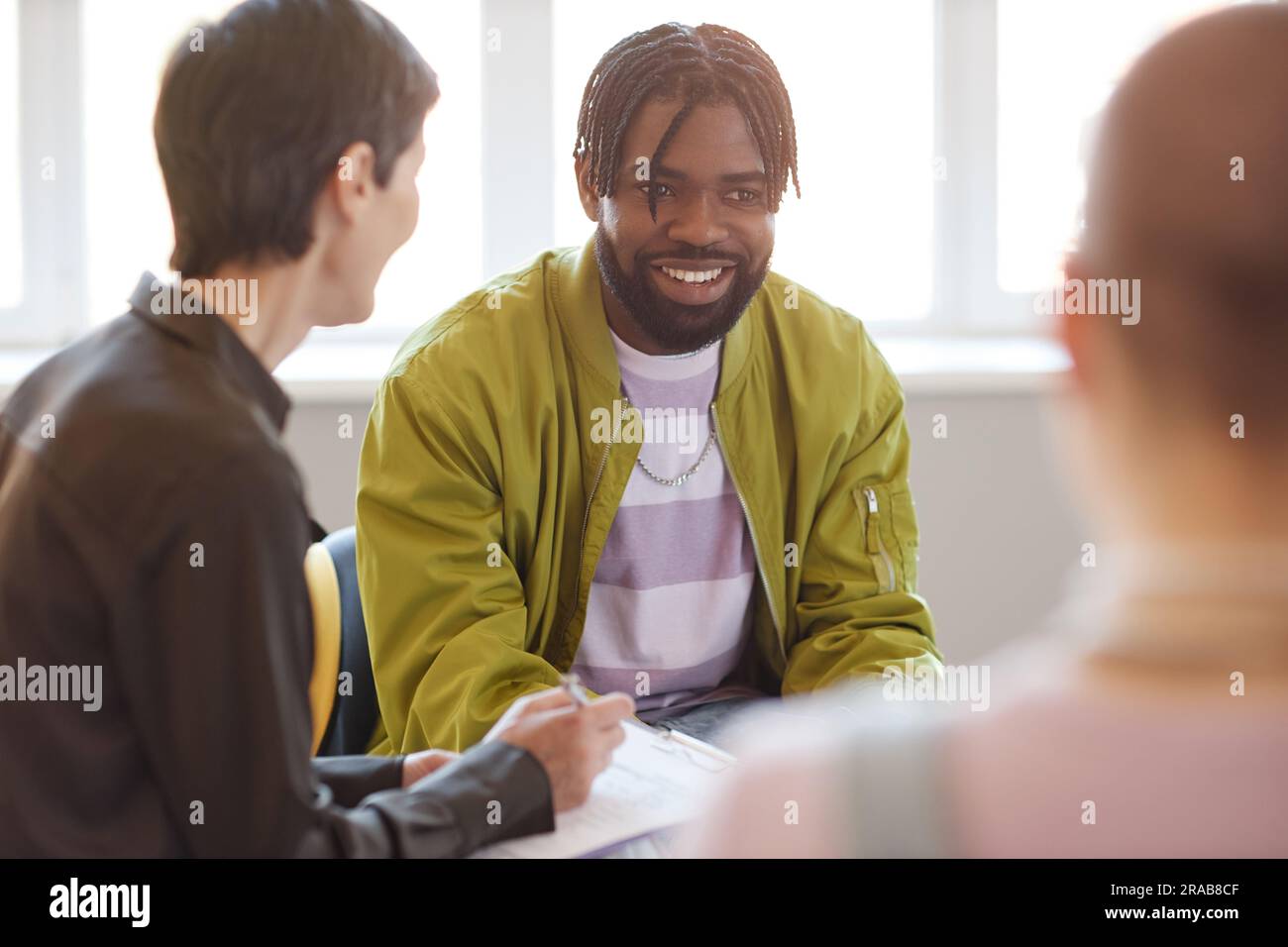 Ein afroamerikanischer Mann, der während einer Psycho-Sitzung im Raum mit Leuten spricht Stockfoto