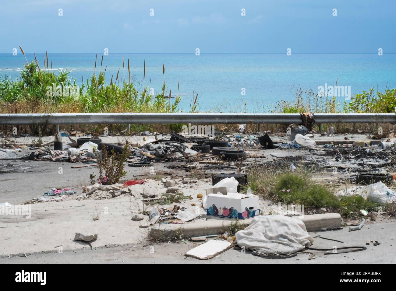 Spontane Müllhalde entlang der Straße mit Blick auf das Meer. Stockfoto