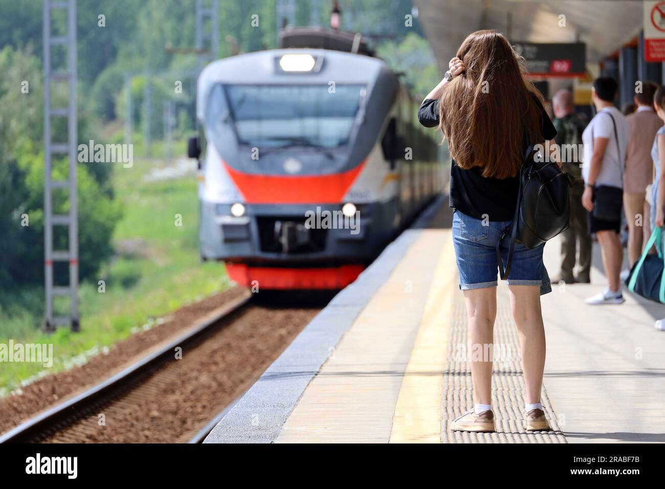 Leute, die auf den ankommenden Zug am Bahnhof warten. Pendlerzugpassagiere im Sommer Stockfoto