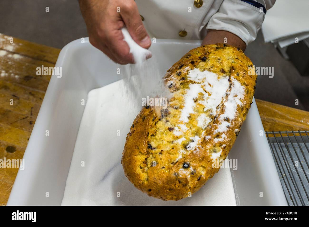 Herstellung eines Dresdner Christstollens in Dresden. Nach der Butter wird der Stollen von oben mit Kristallzucker bestreut. Der Boden darf dagegen keine Butter und keinen Zucker bekommen Stockfoto