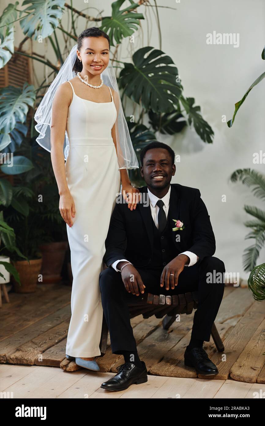 Langes Hochzeitsporträt eines schwarzen jungen Paares als Braut und Bräutigam in orangerie Stockfoto