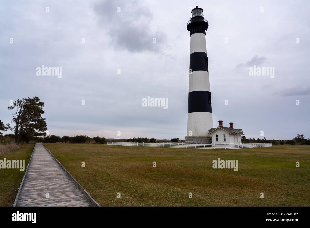 Blick auf den Woddded Path zum Horizont mit großem Leuchtturm an der Seite Stockfoto