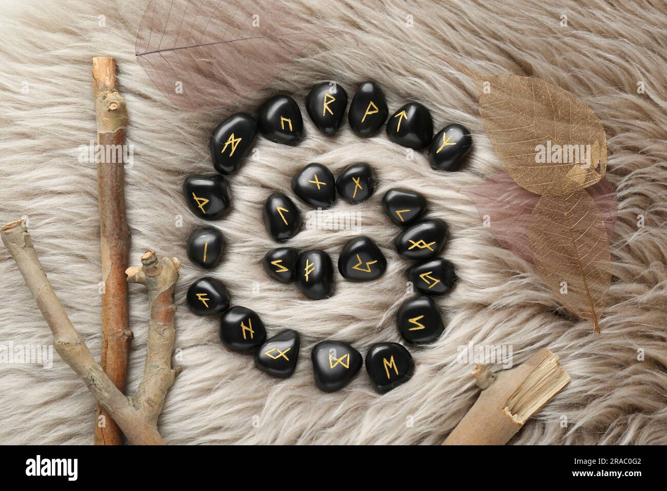 Flache Laienzusammensetzung mit schwarzen Runensteinen auf leichtem Kunstfell Stockfoto