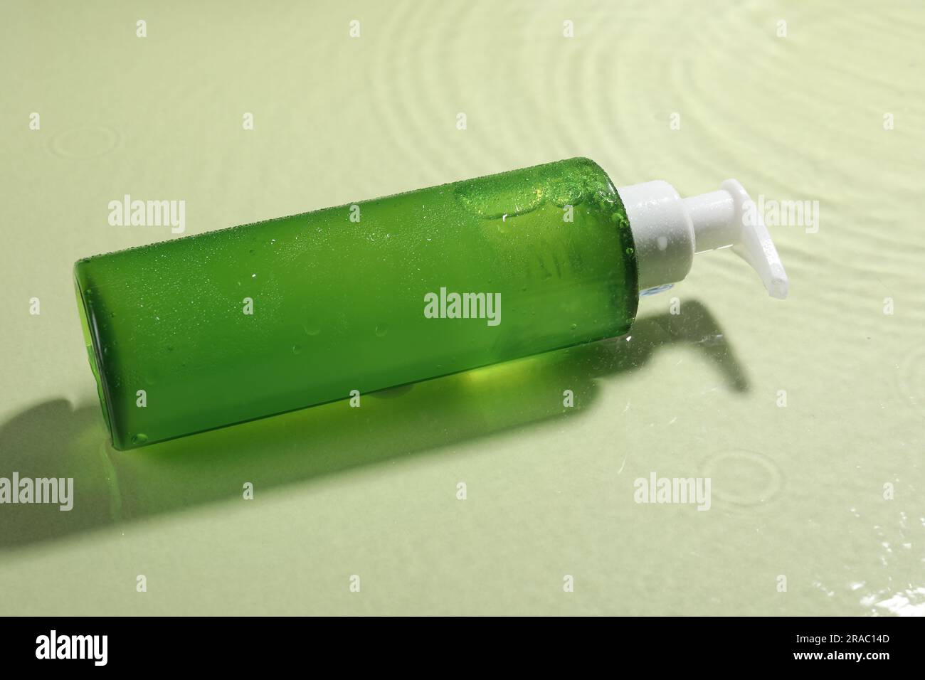 Eine Flasche Gesichtsreiniger in Wasser vor Olivenhintergrund Stockfoto