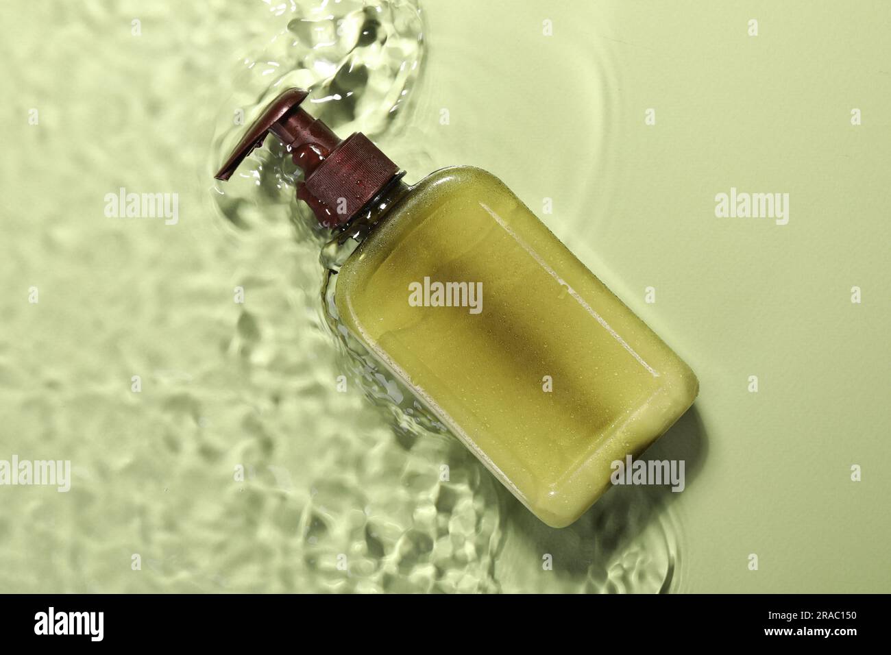 Flasche Gesichtsreiniger in Wasser vor olivem Hintergrund, Draufsicht Stockfoto
