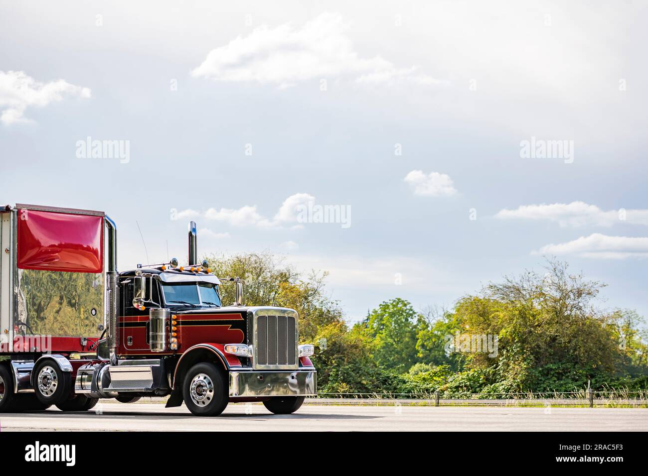 Industrieller amerikanischer Day Cab im alten Stil, burgunderrot, großer Sattelschlepper mit hohem Chromrohr, der Fracht in einem spoi in Rot transportiert Stockfoto