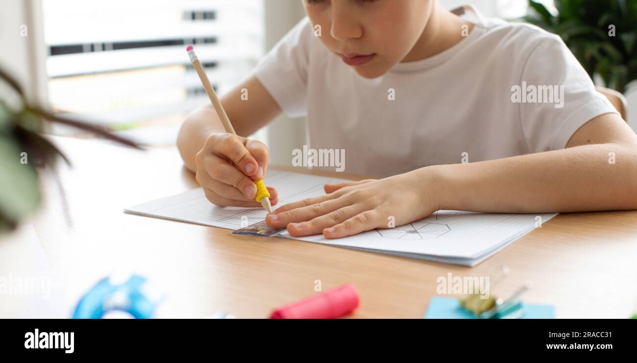 Ein süßer Junge zeichnet mit Lineal und Bleistift. Hausunterricht. Geometrie und Zeichnung. Stockfoto