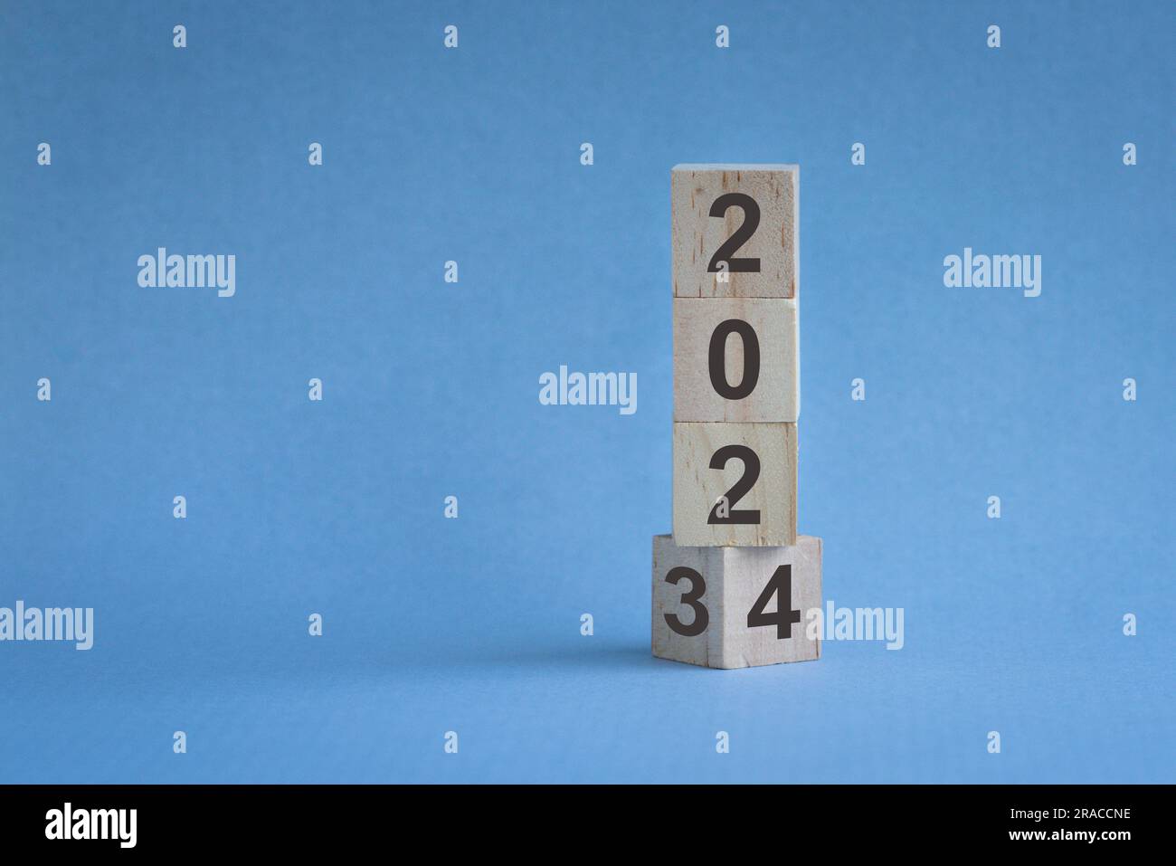 Holzwürfel oder -Blöcke stapeln sich auf dem Tisch, Jahreswechsel von 2023 bis 2024. Auf blauem Hintergrund. Stockfoto