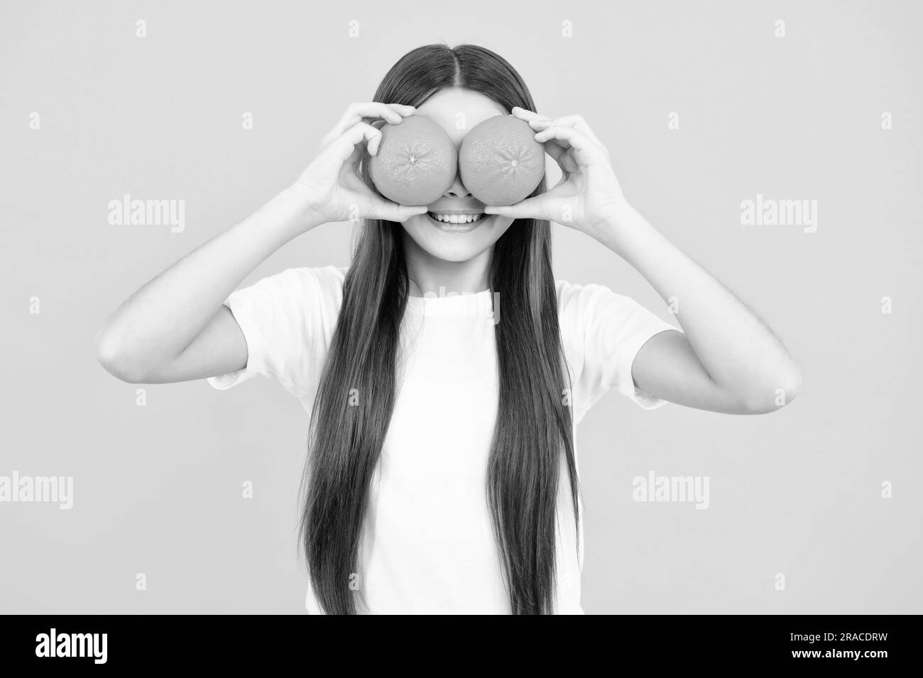 Lustiges Teenager-Portrait. Happy Teenager Mädchen halten Grapefruit Orangeisoliert auf gelbem Hintergrund, Kinder Früchte Vitamin. Stockfoto