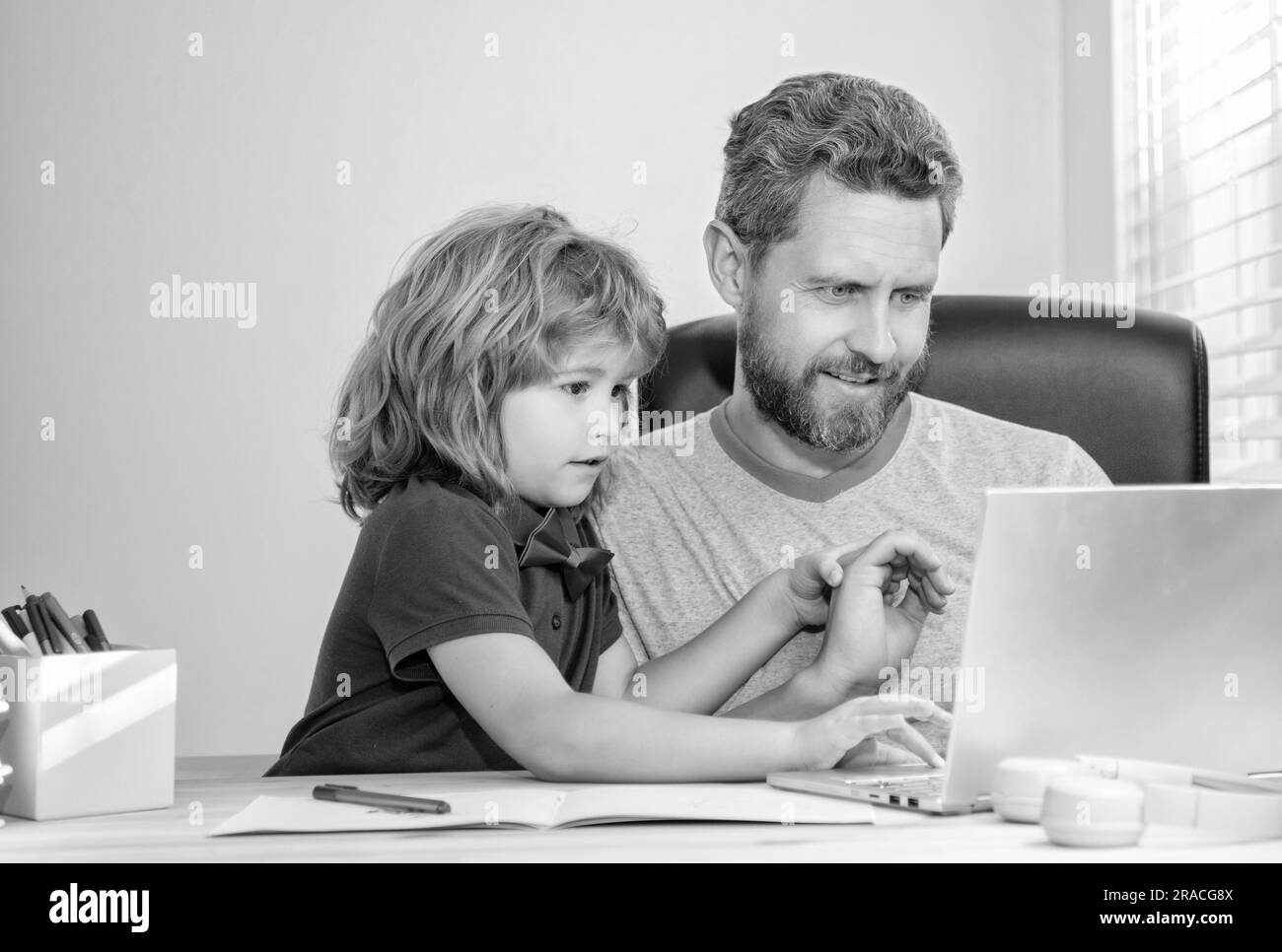 Zurück in die Schule. Dad und Sohn benutzen zu Hause Computer. Familien- und Elternblog. Der Junge macht Hausaufgaben mit einem Privatlehrer. Webinar-Video-Lektion. Online-Bildung Stockfoto