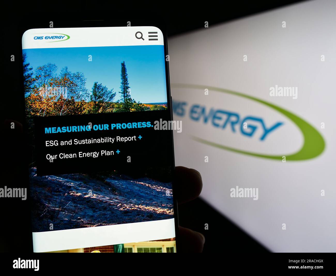 Person, die ein Mobiltelefon mit einer Webseite des US-Versorgungsunternehmens CMS Energy Corporation auf dem Bildschirm vor dem Logo hält. Konzentrieren Sie sich auf die Mitte des Telefondisplays. Stockfoto