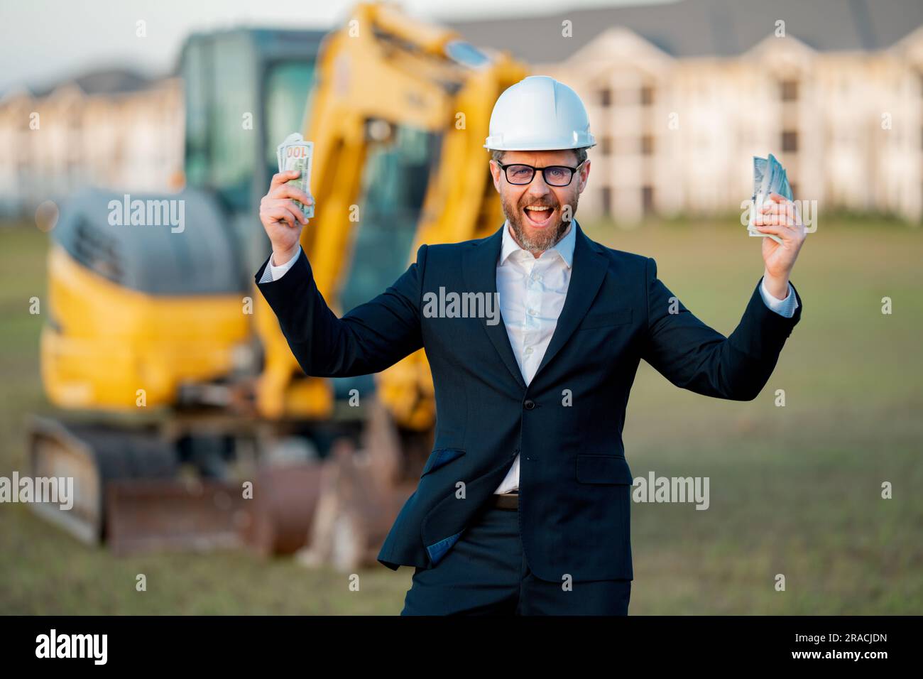 Bauleiter in Anzug und Helm auf einer Baustelle. Bauleiter oder Aufseher tragen Schutzhelm vor dem Haus. Vorgesetzter Stockfoto