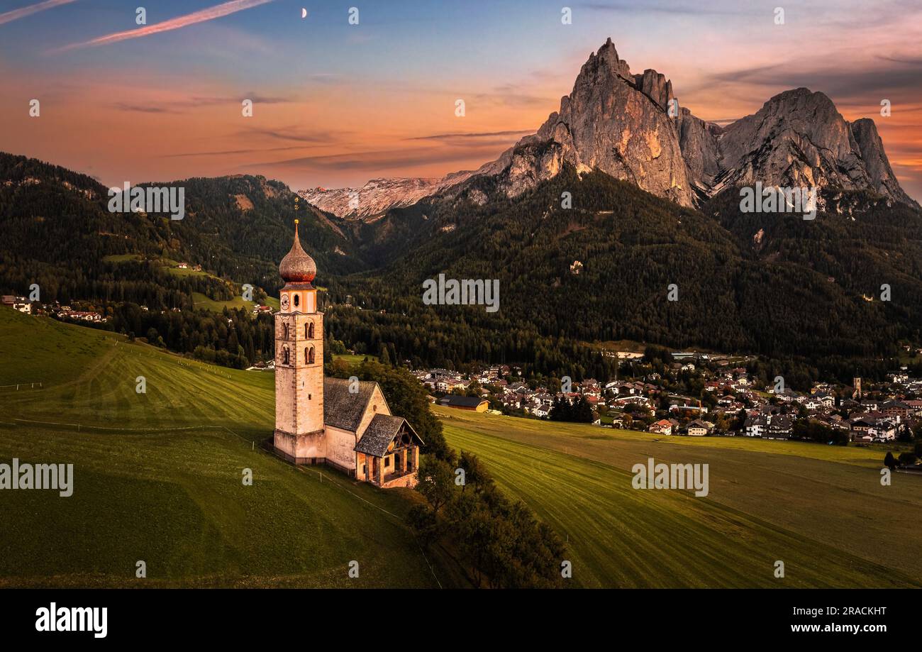 Seis am Schlern, Italien - Panoramablick auf St. Valentin Kirche und der berühmte Berg Sciliar im Hintergrund mit farbenfrohem Sonnenuntergang und Krieg Stockfoto