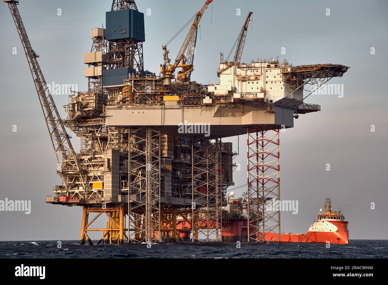 Nahaufnahme der Offshore-Plattform für Öl und Gas mit Versorgungsschiff, das Frachtaktivitäten im Meer durchführt. Stockfoto