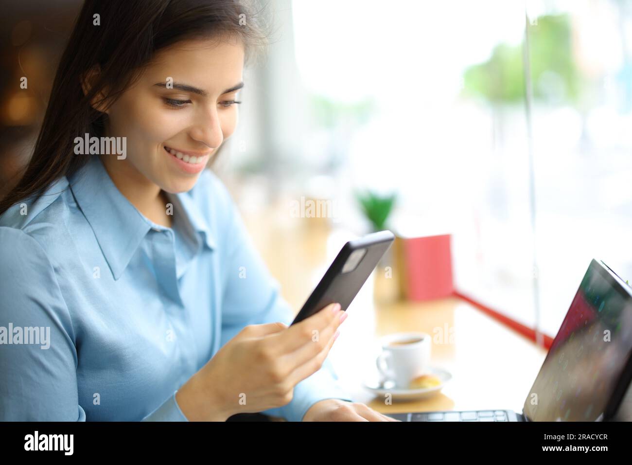 Glückliche Frau, die Handy und Tablet in einer Bar benutzt Stockfoto