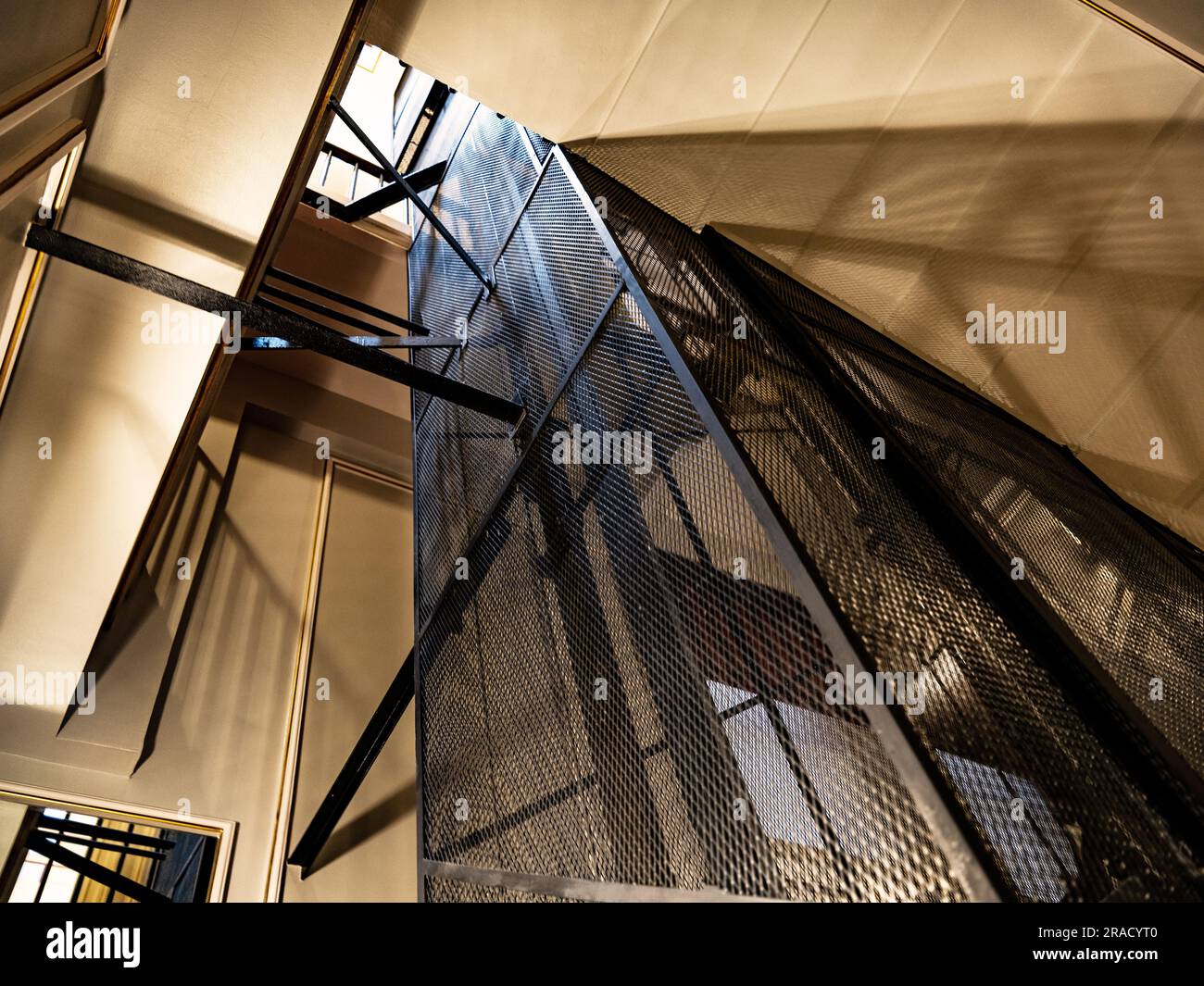 Das Innere des frühen Victorian Pall Mall Clubs zeigt einen Fahrstuhl mit Stahlrahmen (Fahrstuhl) und schattige Beleuchtung, mit einem sehr niedrigen Winkel. Stockfoto