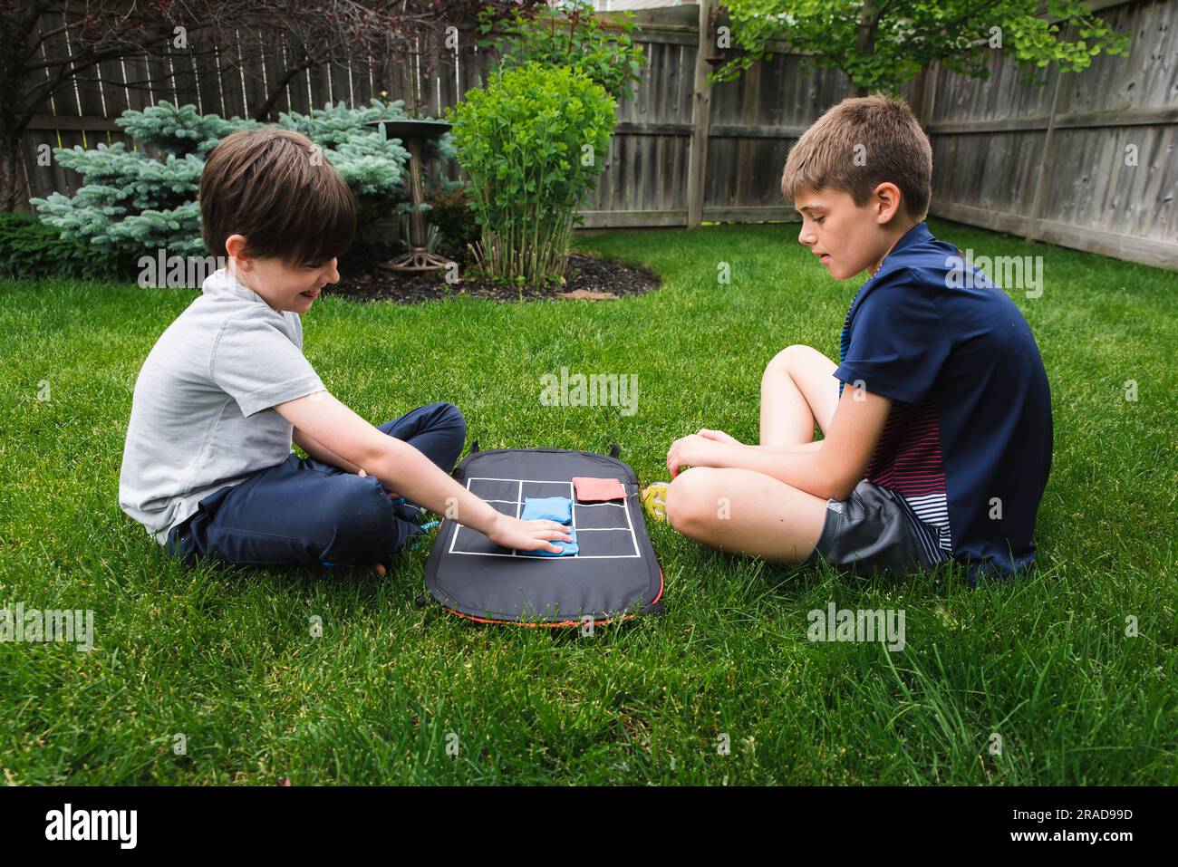 Zwei junge Jungs spielen ein Tic-tac-Toe-Spiel im Hinterhof zusammen. Stockfoto