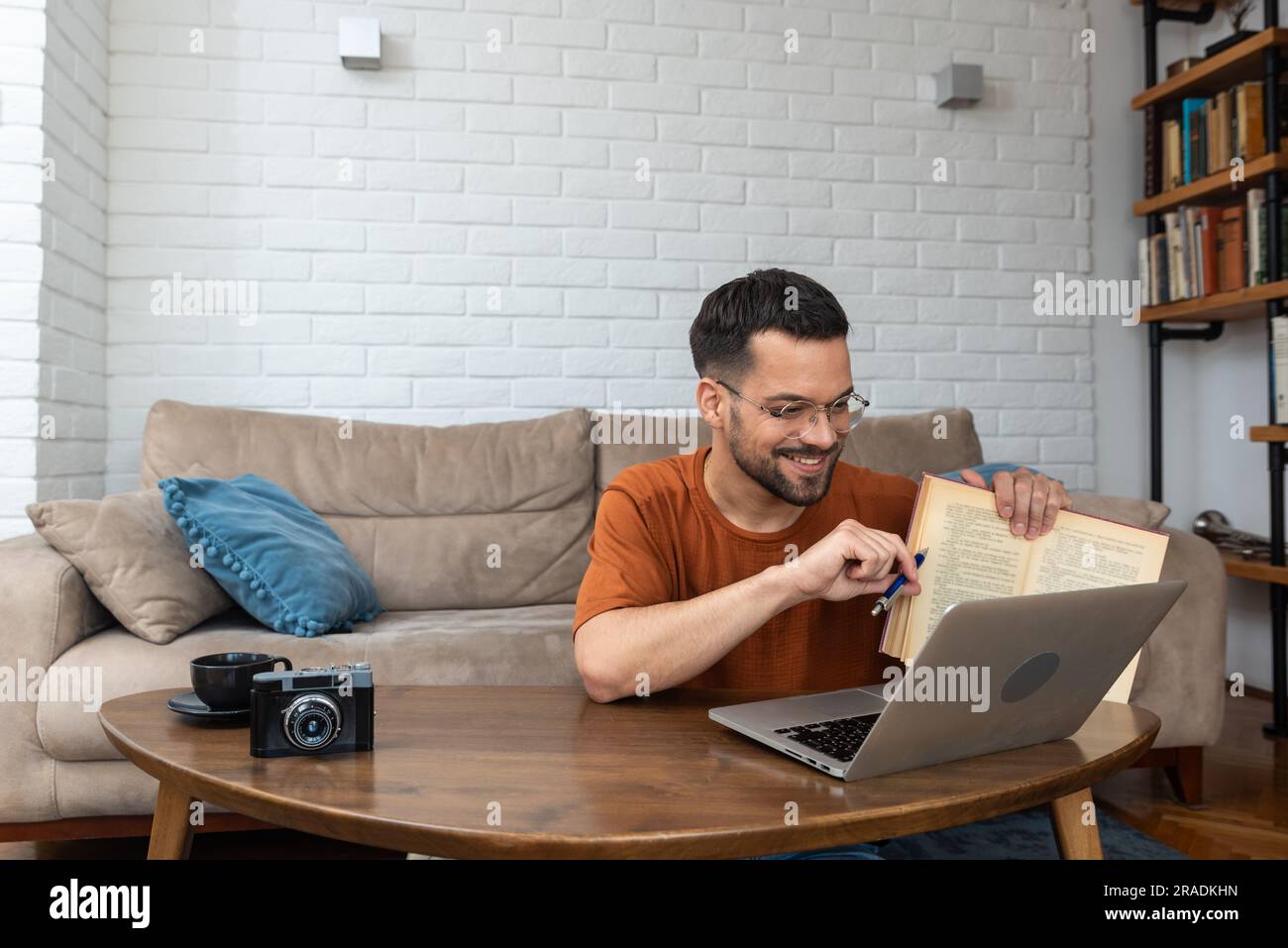 Ein junger, intelligenter Student, der zu Hause auf dem Boden sitzt und als freiberuflicher, entfernter Fremdsprachenprofessor arbeitet und den Leuten englisch beibringt Stockfoto